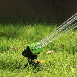Arroseur de jardin posé dans une pelouse et jetant de l'eau.