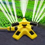Arroseur de jardin rotatif jaune posé près d'une pelouse.