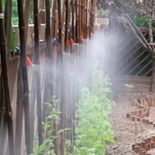 Photo d'un arrosage par brumisation automatique sur une palissade avec plantes vertes en bas