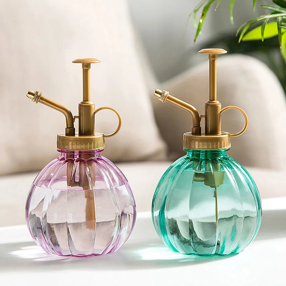 Mini arrosoir vert et rose à piston et posé sur une table.