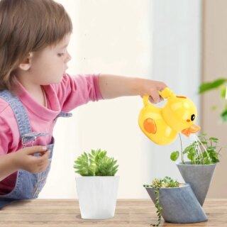 Petite fille utilisant un arrosoir en forme de canard pour arroser des plantes en pot.
