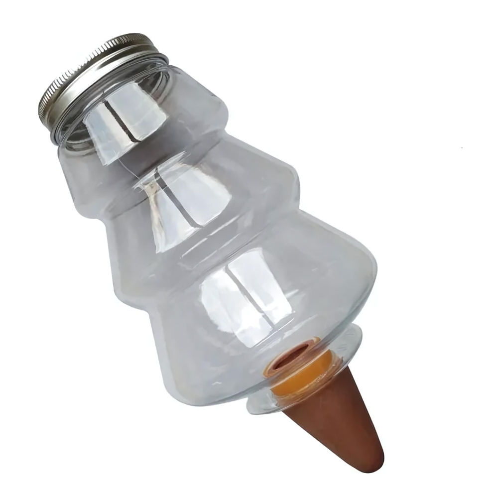 Récipient en forme de sapin en plastique avec bouchon au-dessus en métal pour arrosage goutte à goutte. L'embout pointu à planter dans la terre est orange. Sur fond blanc.